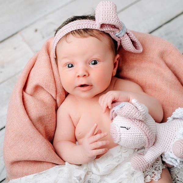 baby lachend mit schleife und kuscheltier