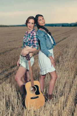 zwei frauen mit gitarre im feld